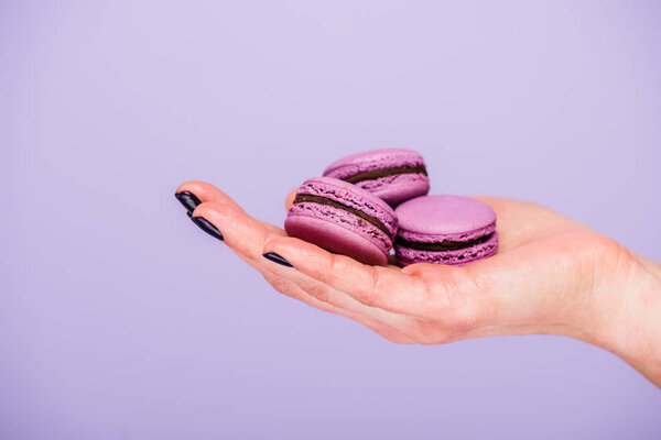 Female hand with macarons isolated on violet