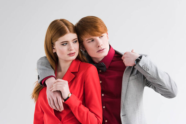 Young couple of fashion models with wristwatches isolated on grey