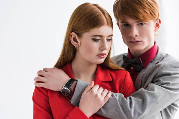 Young male fashion model with wristwatch holding girlfriend shoulder isolated on grey