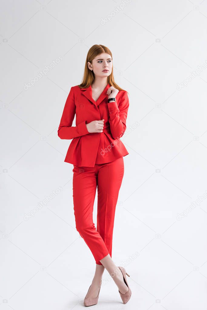 Stylish young female dressed with wristwatch dressed in suit isolated on grey