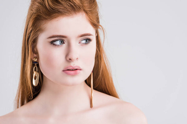 Portrait of young female model with earrings isolated on grey