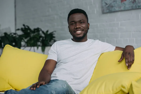 Retrato Joven Afroamericano Guapo Sentado Sofá Sonriendo Cámara —  Fotos de Stock