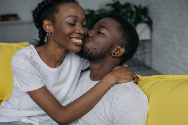 beautiful happy young african american couple hugging and kissing at home