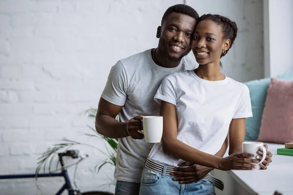 Gelukkige Jonge Afro Amerikaanse Paar Kopjes Bedrijf Lachend Camera — Stockfoto