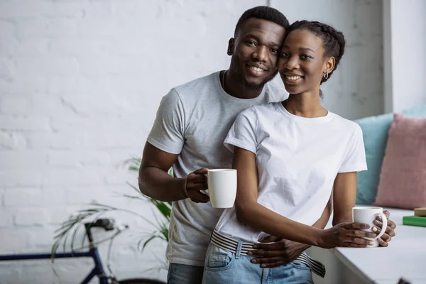 Feliz Joven Afroamericano Pareja Sosteniendo Tazas Sonriendo Cámara — Foto de Stock