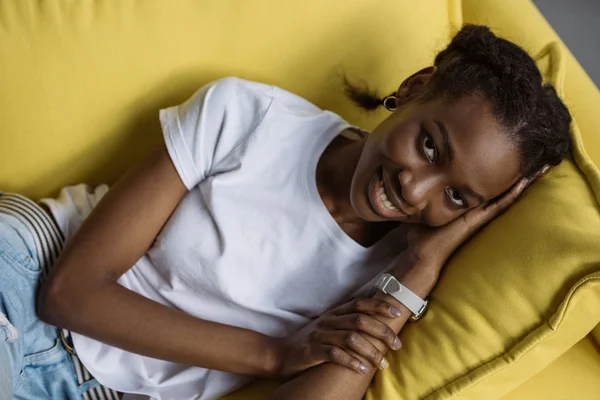 Beautiful Young African American Woman Lying Sofa Smiling Camera — Free Stock Photo