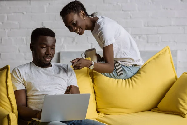 Glada Unga Afroamerikanska Par Använder Laptop Medan Sitter Soffan Hemma — Stockfoto
