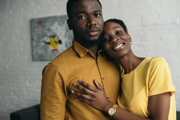年轻的非洲裔美国夫妇在黄色的衬衫站在一起 看着在家里的相机 — 图库照片