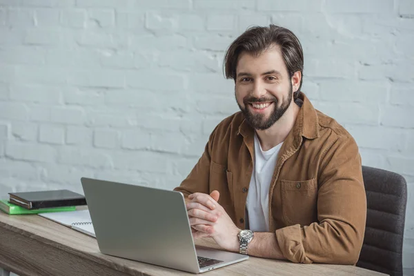 Sorridente Bonito Empresário Sentado Mesa Com Laptop Olhando Para Câmera — Fotografia de Stock