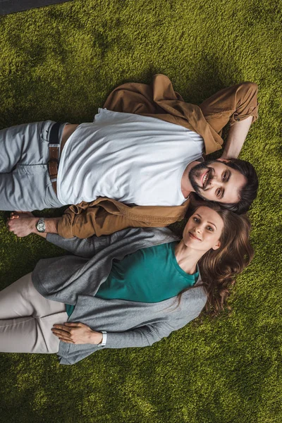 Bovenaanzicht Van Aantrekkelijke Paar Liggend Het Groene Tapijt Thuis — Gratis stockfoto