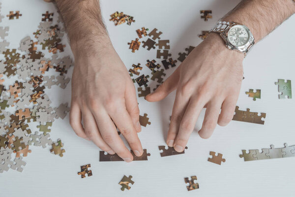 cropped image of man connecting puzzle pieces at table