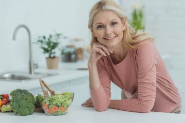 Mutfakta sayaçta taze salata ile gülümseyen Olgun kadın portresi