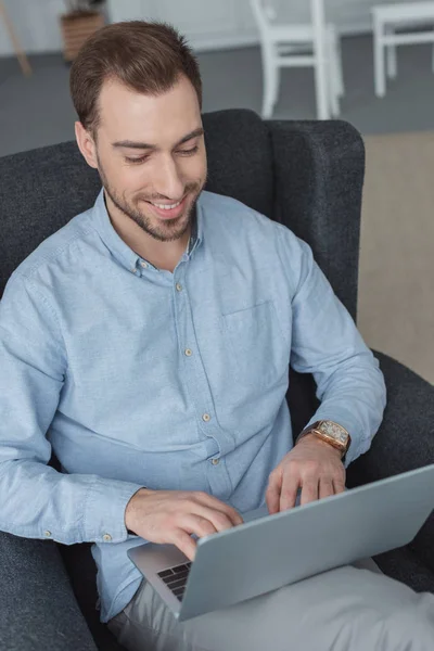 Προσωπογραφία Άνδρα Χαμογελώντας Χρησιμοποιώντας Φορητό Υπολογιστή Ενώ Ξεκουραζόταν Πολυθρόνα — Δωρεάν Φωτογραφία