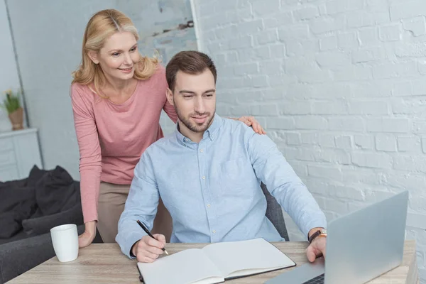 Retrato Madre Sonriente Hijo Crecido Mesa Con Portátil Portátil Casa — Foto de stock gratuita