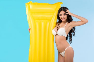 Mavi izole sarı şişme yatak ile gülümseyen güzel kadın