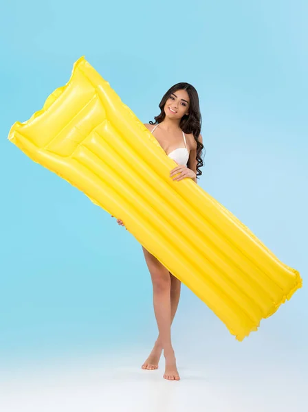 美丽的年轻女子摆着黄色充气床垫 蓝色隔离 — 图库照片
