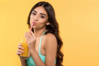 güzel genç kadın ile bardak meyve suyu, izole sarı bikinili poz