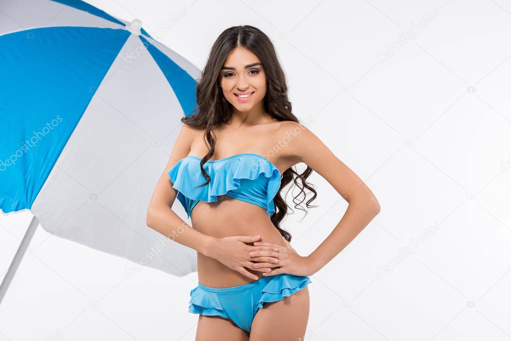 beautiful tanned girl in bikini posing at beach umbrella, isolated on white