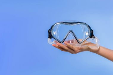 cropped view of female hand with swimming goggles, isolated on blue clipart