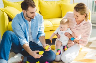 Onu elinde tutan anne ise bebek kızı ile oynarken baba