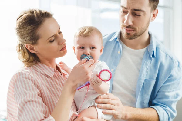 Young Mother Giving Baby Dummy Infant Daughter While Father Touching — Stock Photo, Image