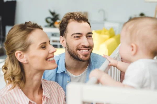 Smiling Parents Watching Infant Daughter Standing Crib — Stock Photo, Image