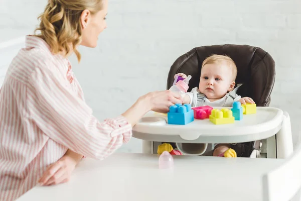 Mother Feeding Infant Daughter Sitting Baby Chair Plastic Blocks — Stock Photo, Image