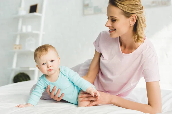 Sorrindo Mãe Segurando Bebê Filha Cama — Fotografia de Stock