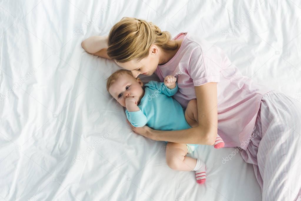 High angle view of smiling mother with infant daughter in bed