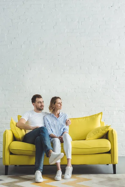 Young Man Embracing Girlfriend Yellow Sofa Modern Room — Stock Photo, Image