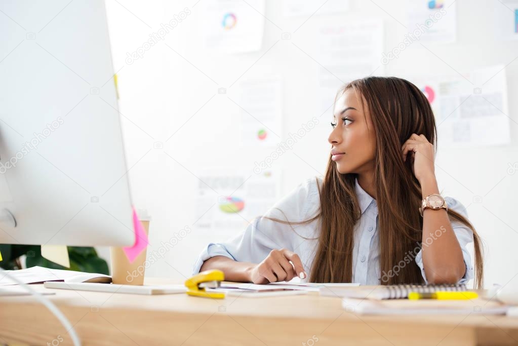 pensive african american businesswoman looking away at workplace in office