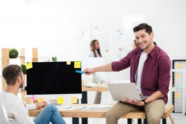 meslektaşım Office ile işyerinde çalışırken boş bilgisayar ekranı işaret eden işadamı