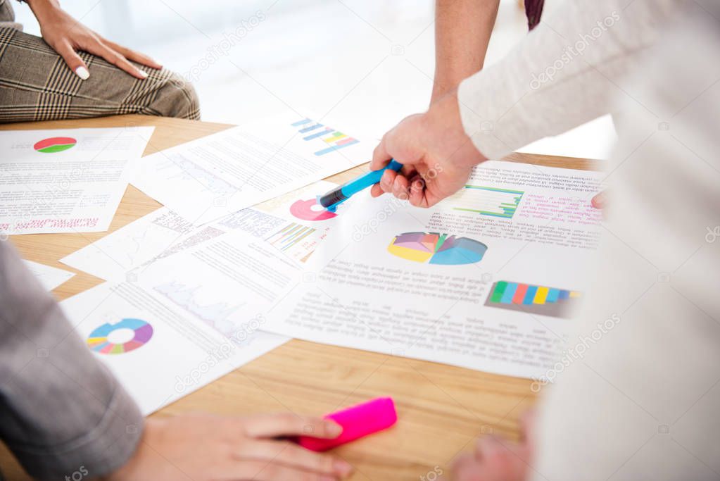 cropped shot of multiethnic business colleagues discussing new marketing project at workplace in office