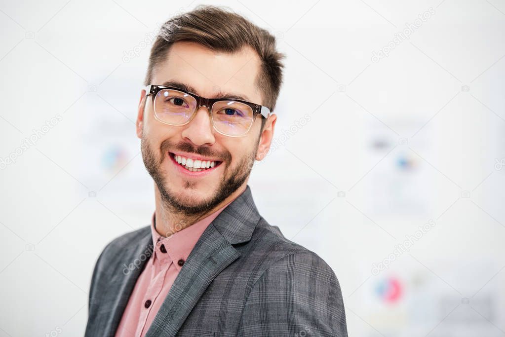 portrait of smiling businessman in suit and eyeglasses looking at camera