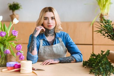 İşyerinde oturan ve çiçekçi dükkanı kamerada bakarak güzel genç çiçekçi