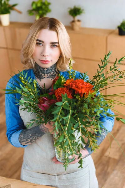 Attraktiv Kvinnelig Blomsterhandler Som Holder Blomsterbukett Ser Kamera – stockfoto