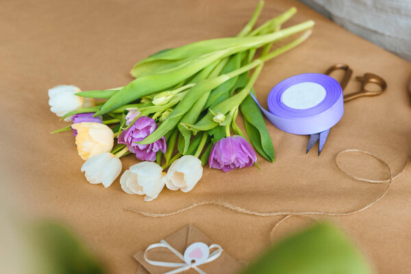 close-up view of beautiful tender tulips, rope, ribbon and scissors on craft paper
