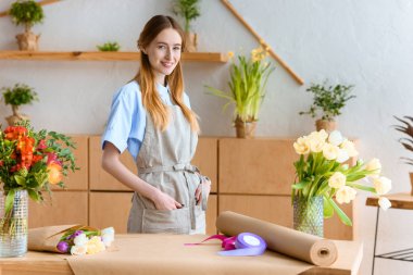 cepler ve çiçekçi dükkanı kameraya gülümseyen genç çiçekçi ile önlük ayakta eller