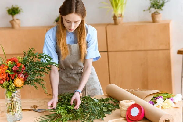 フラワー ショップの緑の植物を配置するエプロンの美しい若い花屋 — ストック写真