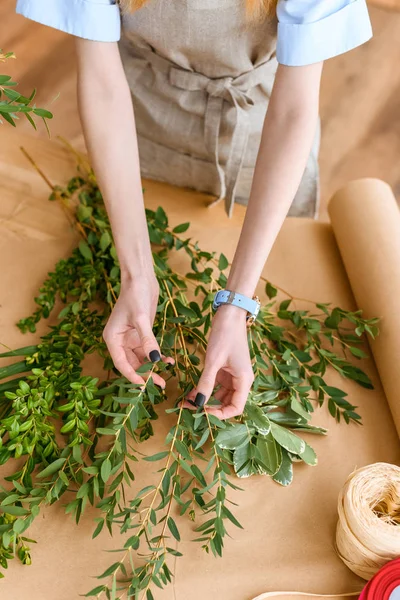 フラワー ショップの緑の植物を配置するエプロンの若い花屋のショットをトリミング — ストック写真