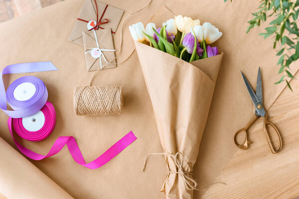 Top view of beautiful bouquet of tulips, scissors, ribbons and envelopes with rope on craft paper — Stock Image Top View Beautiful Bouquet Tulips Scissors Ribbons Envelopes Rope Craft Royalty Free Stock Images