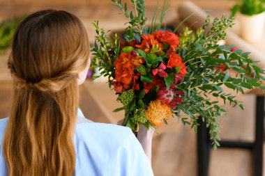 back view of young florist holding beautiful flower bouquet clipart