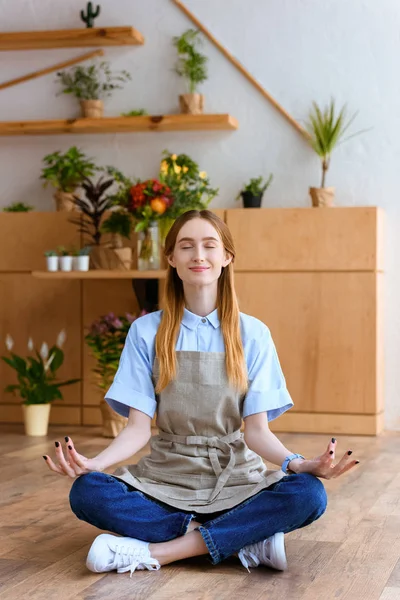 Smiling Young Florist Apron Sitting Lotus Position Floor Flower Shop — Free Stock Photo