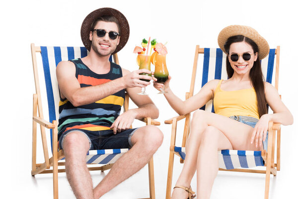 couple relaxing on beach chairs and clinking glasses with cocktails, isolated on white