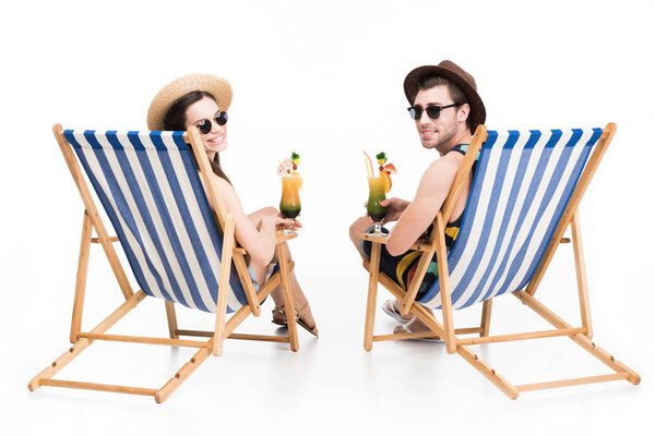 smiling couple relaxing on beach chairs with cocktails, isolated on white