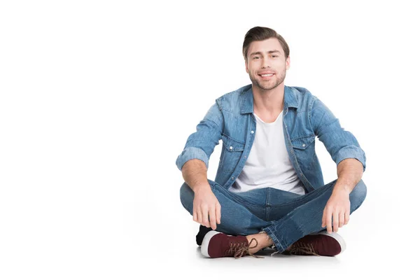 Joven Hombre Sonriente Sentado Jeans Mirando Cámara Aislado Blanco — Foto de Stock