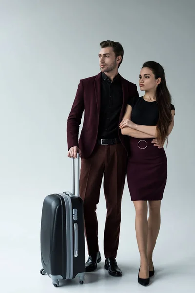 serious couple with luggage ready for trip, isolated on grey