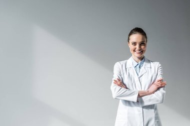Kameraya bakarak çapraz kolları olan mutlu kadın doktor
