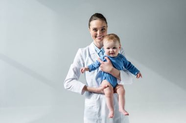 gri çok güzel küçük bebek tutan mutlu kadın çocuk doktoru