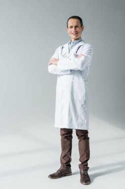 gri izole kamera bakarak çapraz kollu yakışıklı yetişkin doktor